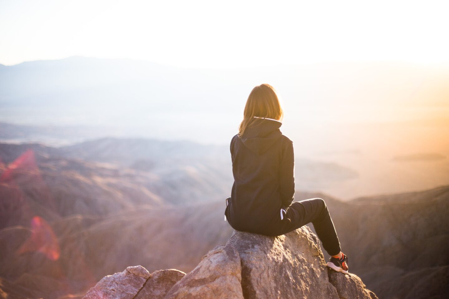 girl sitting on cliffside, facing away