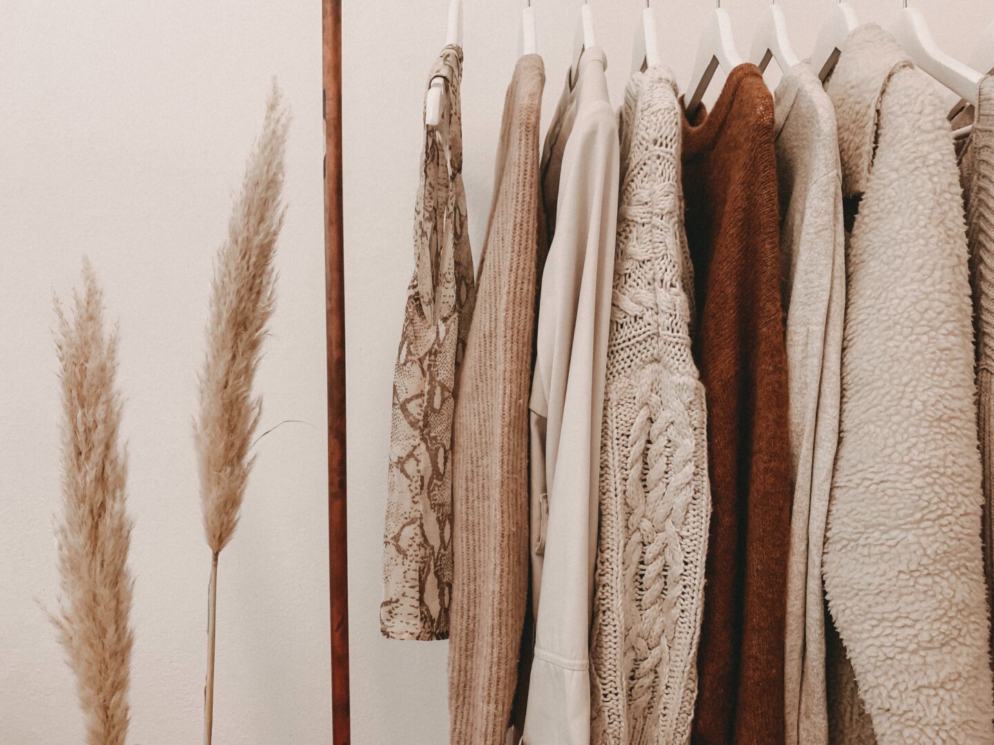 autumn clothes hanging on a rail with wheat stalks on the left